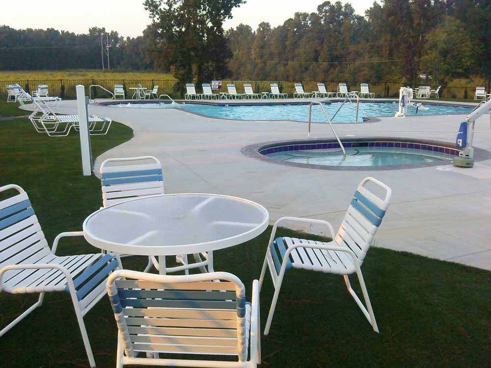 Swimming pool with lounge chairs and table at RALEIGH OAKS RV RESORT & COTTAGES