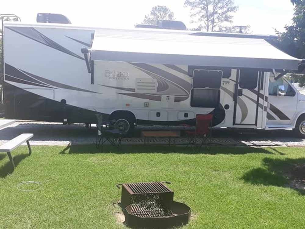 A trailer parked in a gravel site with a fire pit at RALEIGH OAKS RV RESORT & COTTAGES