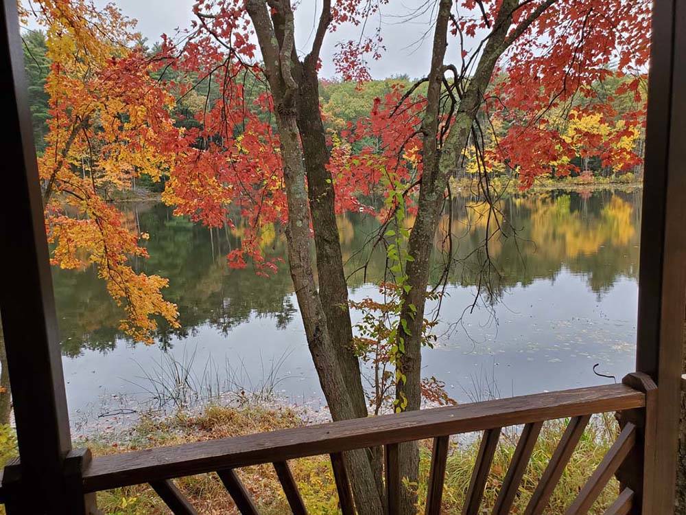 Balcony overlooks a placid lake reflecting autumn trees at PINE LAKE RV RESORT & COTTAGES