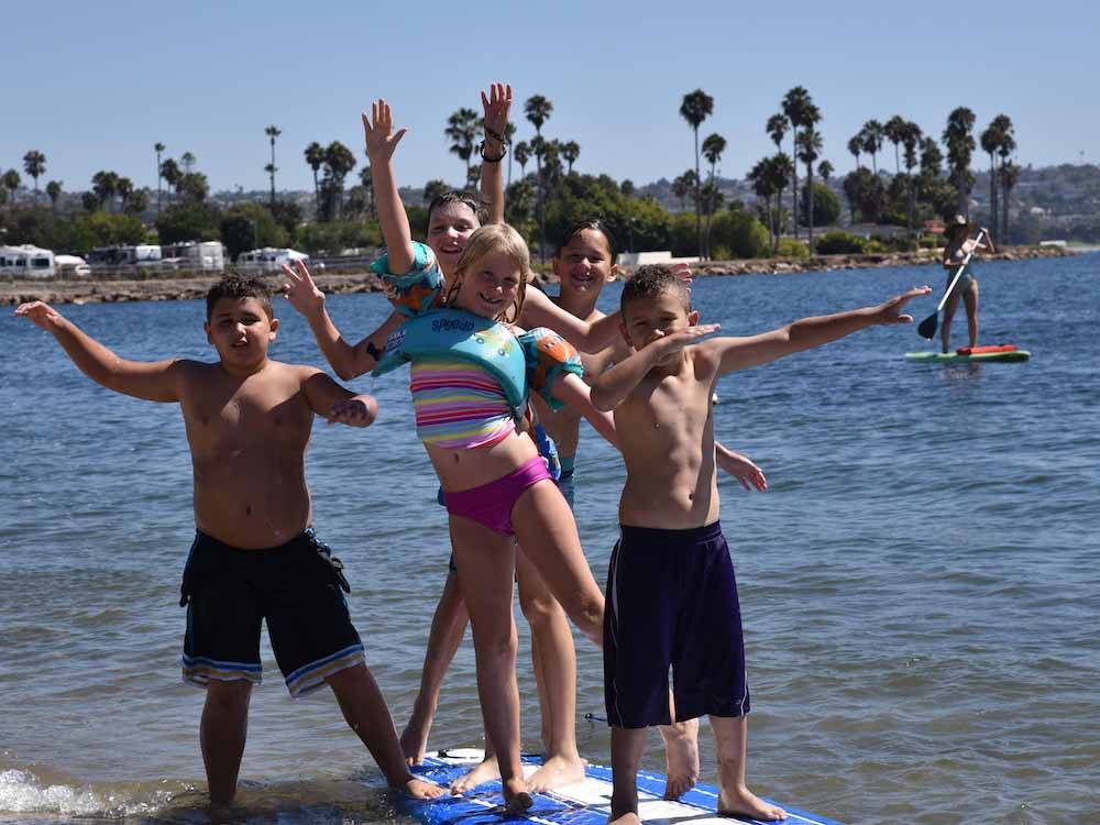 A group of kids posing for the camera on the water at CAMPLAND ON THE BAY