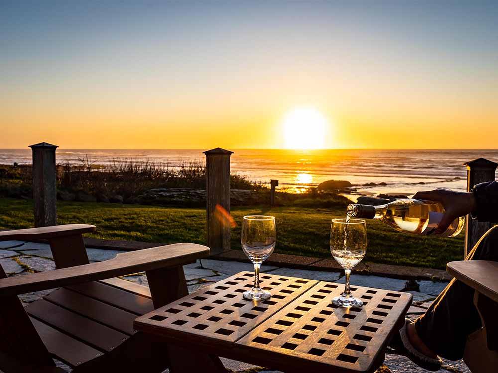 A person pouring wine at sunset overlooking the ocean at SEA PERCH RV RESORT
