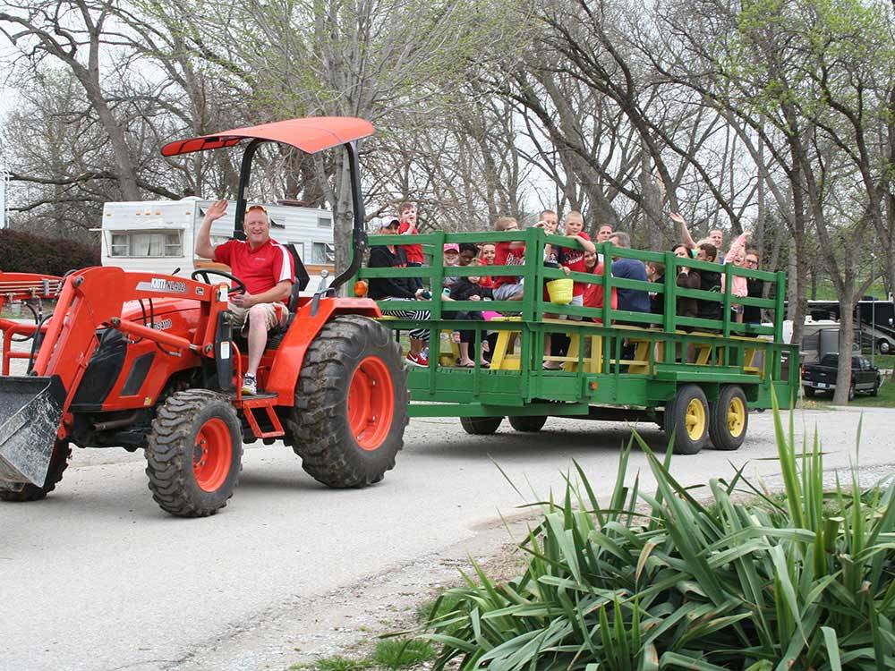 Man driving tractor giving families a ride in a wagon at CAMP A WAY RV PARK