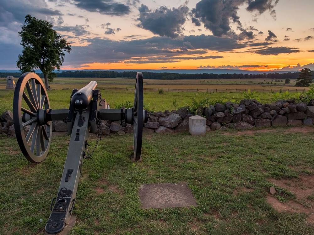 Cannon pointing to expansive field at dusk at GETTYSBURG CAMPGROUND