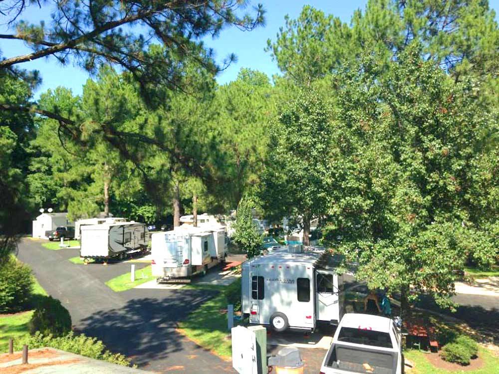 White travel trailers camping at campsite and green trees at AMERICAN HERITAGE RV PARK