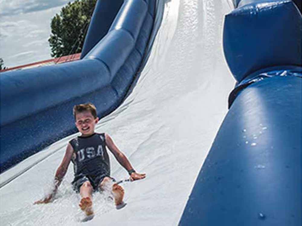 A boy sliding down an inflatable waterslide at CABOOSE LAKE CAMPGROUND