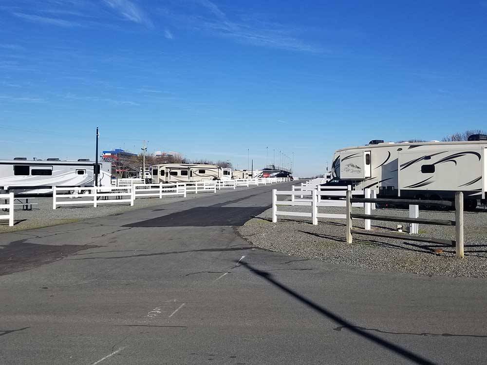 Roadway leading through RV park with trailers and white fencing on both sides at CAMPING WORLD RACING RESORT