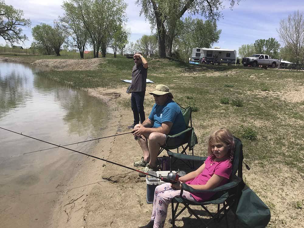 A group of people fishing in the lake at I-80 LAKESIDE CAMPGROUND