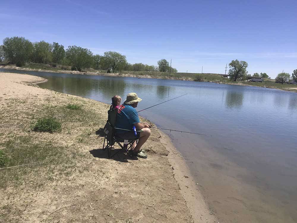 People sitting in chairs fishing at I-80 LAKESIDE CAMPGROUND