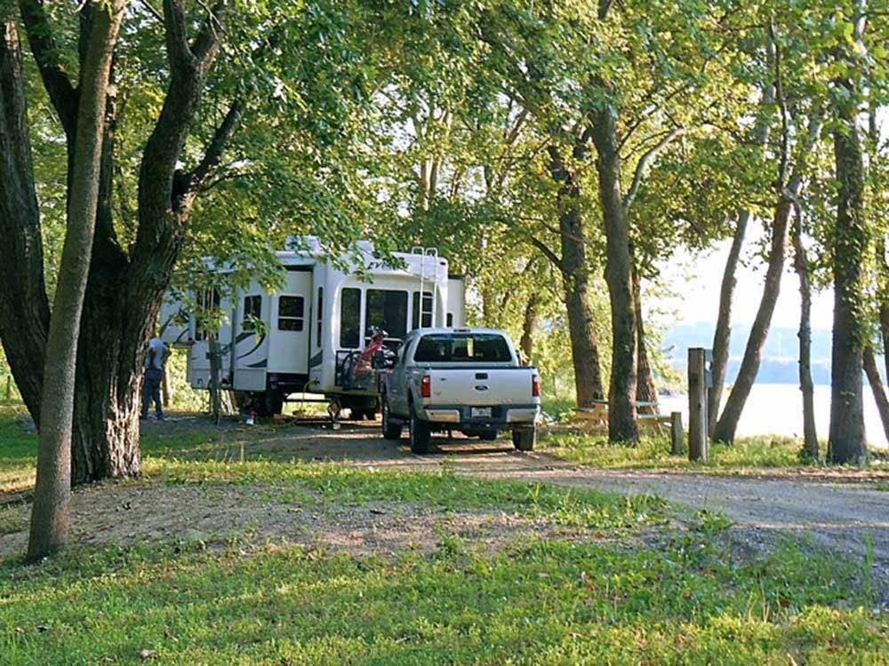 RV and truck in a treed site with lakeview at MILLPOINT RV PARK