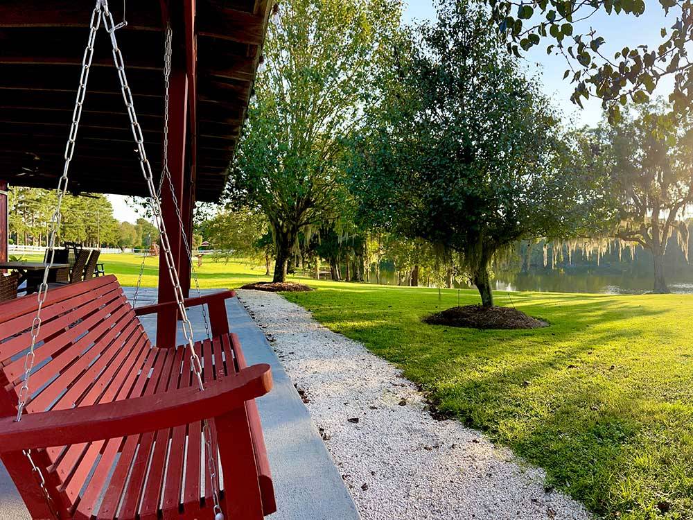 A bench swing looking at a greenery area at RED GATE FARMS - RV RESORT