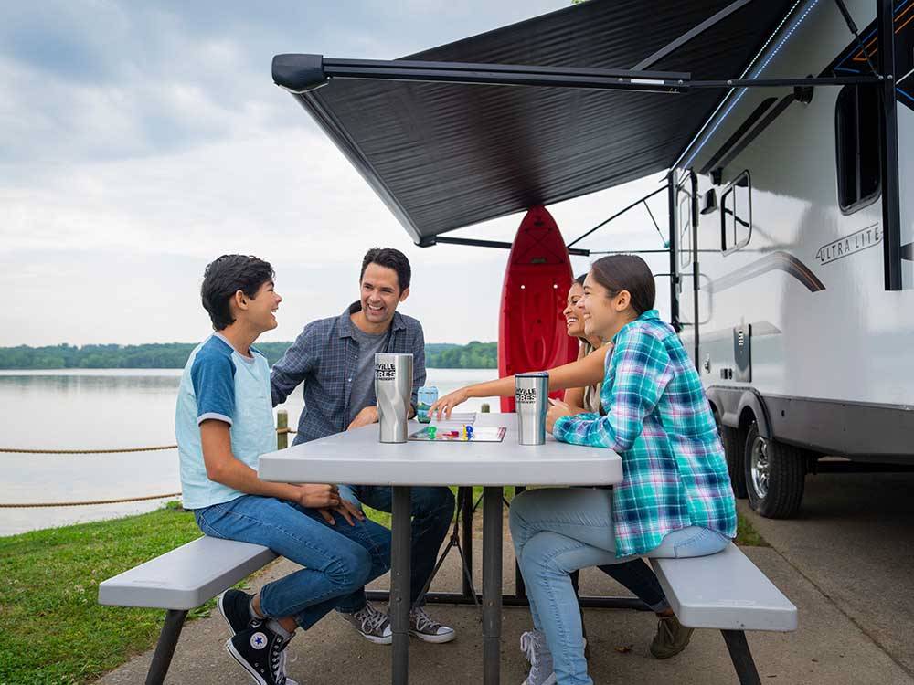 A family sitting at a picnic table outside an RV at NASHVILLE SHORES LAKESIDE RESORT