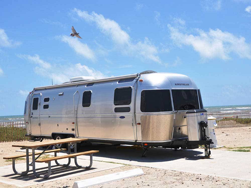 An airstream trailer parked next to a picnic table at DELLANERA RV PARK