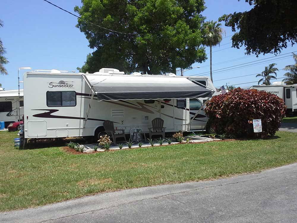 RV backed in with two chairs on patio at BOARDWALK RV RESORT