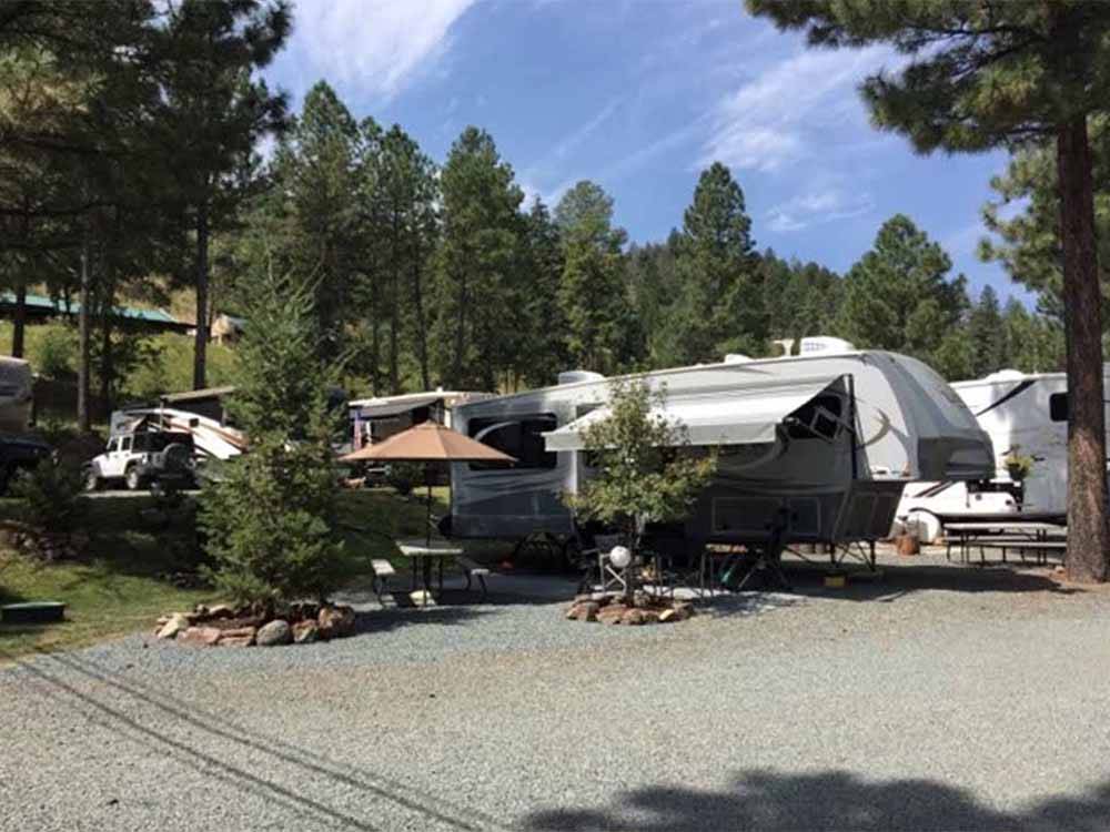 A fifth wheel trailer in a site with a bench at EAGLE CREEK RV RESORT