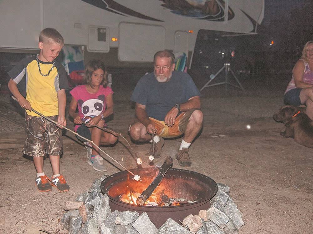 A family roasting marshmallows around a fire at SCENIC MOUNTAIN RV PARK & CAMPGROUND