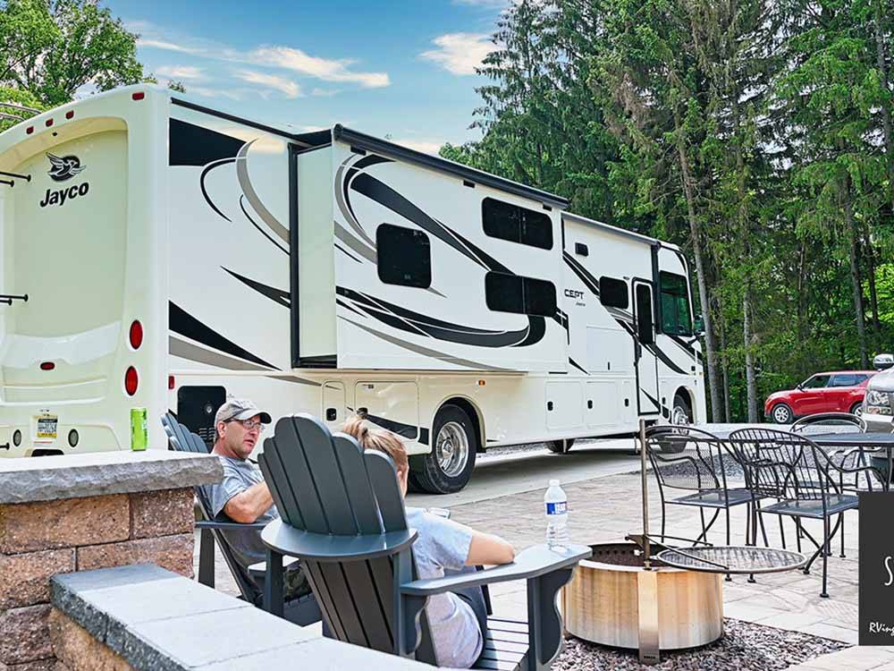 Two people sitting outside of a motorhome at STONYBROOK RV RESORT