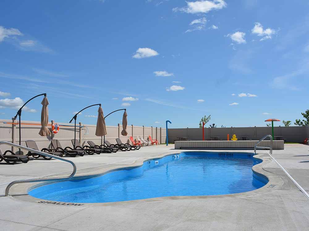 The pool area with lounge chairs and umbrellas at CAMPLAND RV RESORT