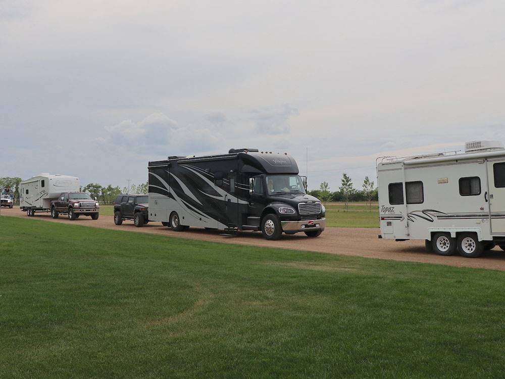 RVs on a road flanked by grassy areas at CAMPLAND RV RESORT