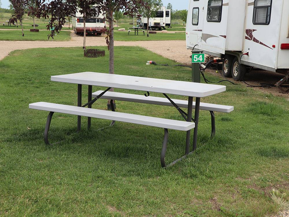 Picnic table on grass outside of RV at CAMPLAND RV RESORT