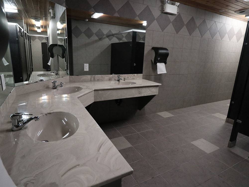 Bathroom with gray tiles and two sinks at CAMPLAND RV RESORT