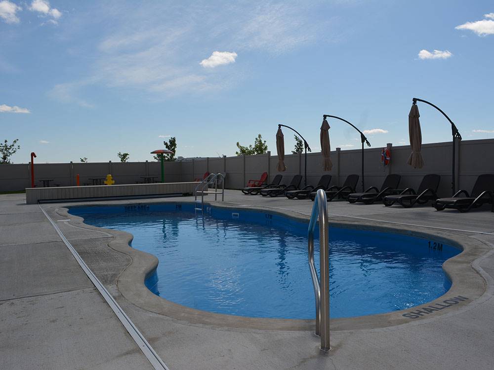 Amoeba-shaped pool with chaise lounges at CAMPLAND RV RESORT