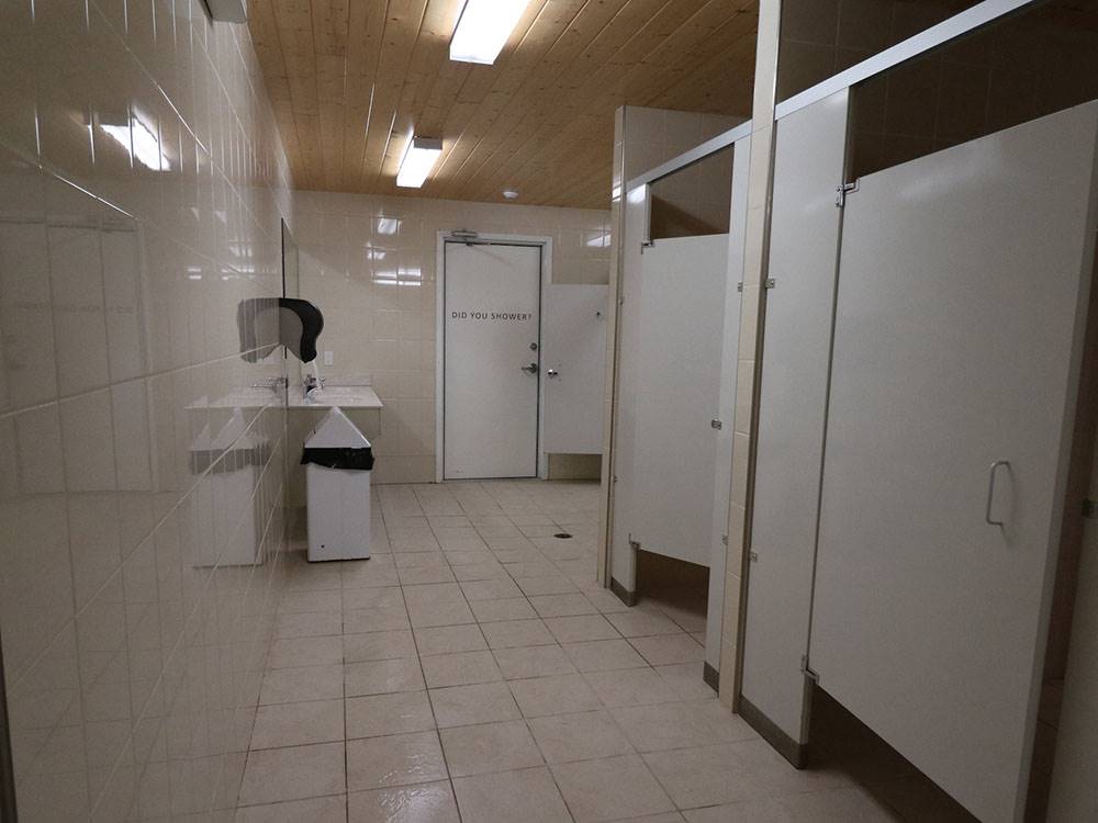 Bathroom with stalls and clean floor at CAMPLAND RV RESORT