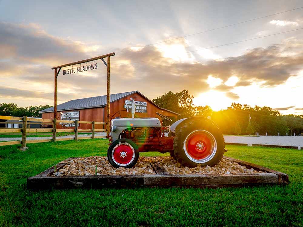 Antique tractor and barn at park entrance at RUSTIC MEADOWS RV PARK