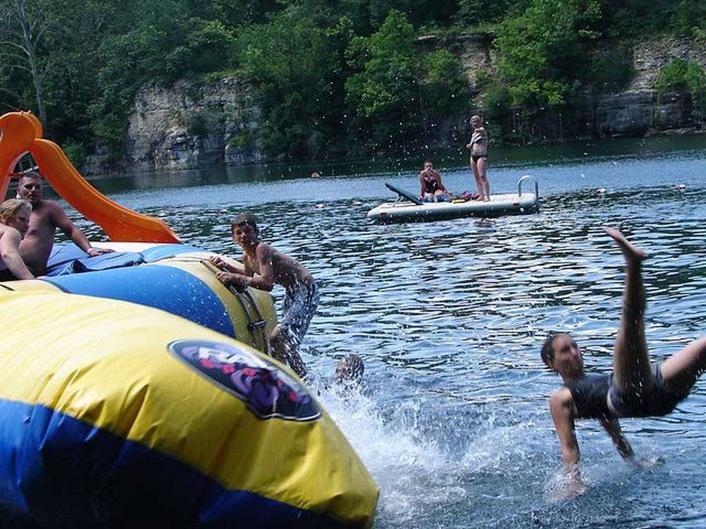 Group of kids playing on yellow and blue inflatable on large lake at HIDDEN PARADISE CAMPGROUND