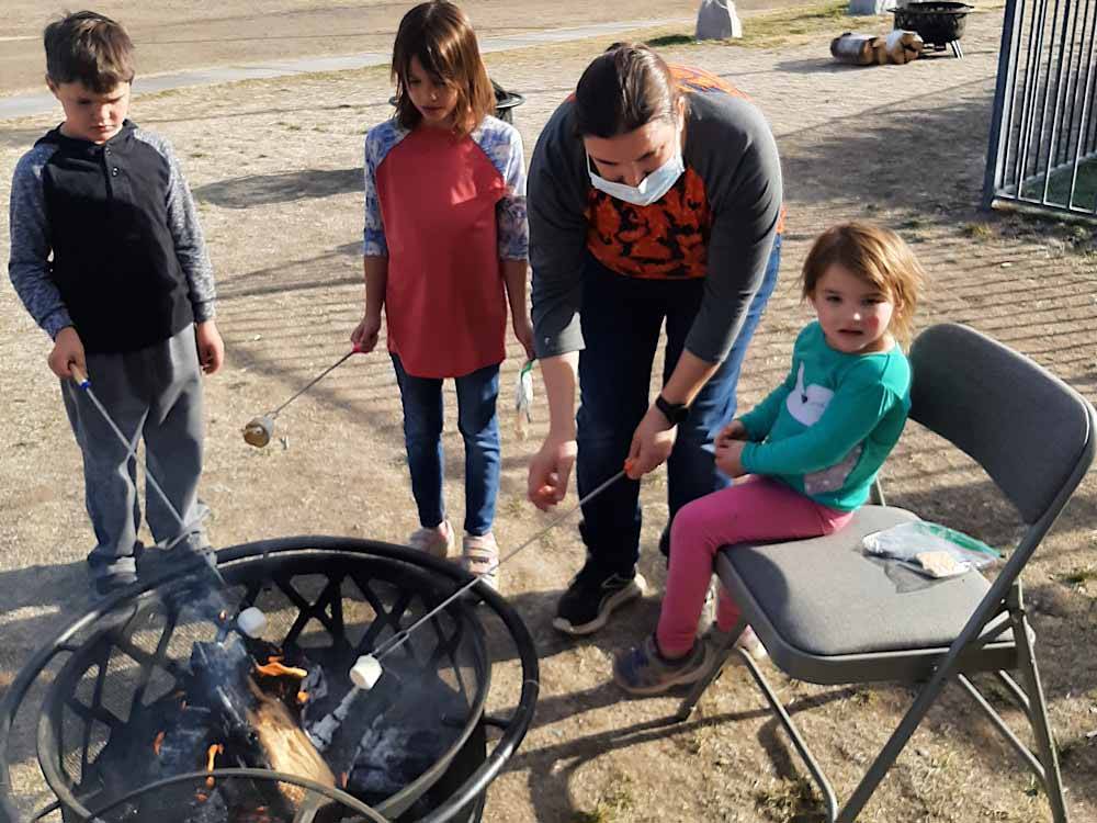 Kids roasting marshmallows over a fire at VERDE RIVER RV RESORT & COTTAGES