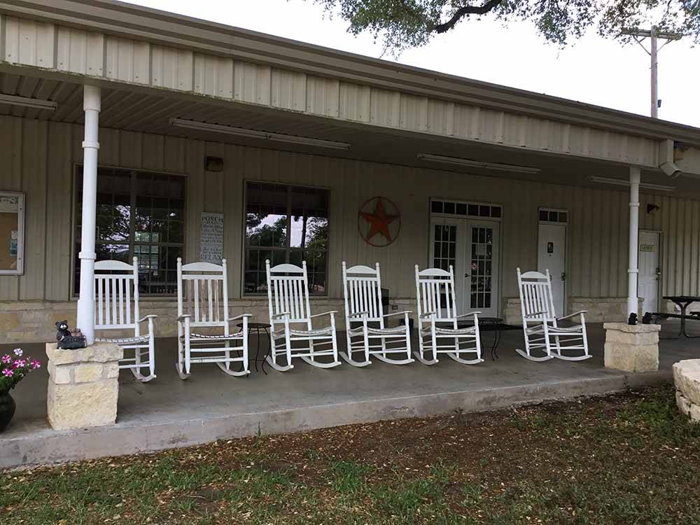A row of white rocking chairs at PEACH COUNTRY RV PARK