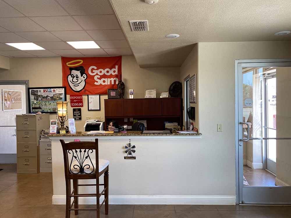 A front desk with chair and Good Sam banner at CLOVIS RV PARK
