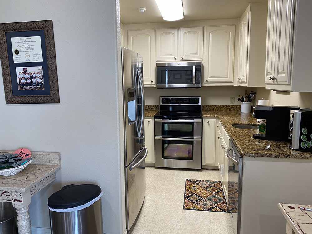 Kitchen area with stainless-steel microwave, oven and sink at CLOVIS RV PARK