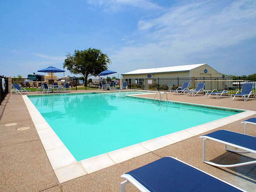 Large swimming pool with blue lounge chairs at SHADY CREEK RV PARK AND STORAGE