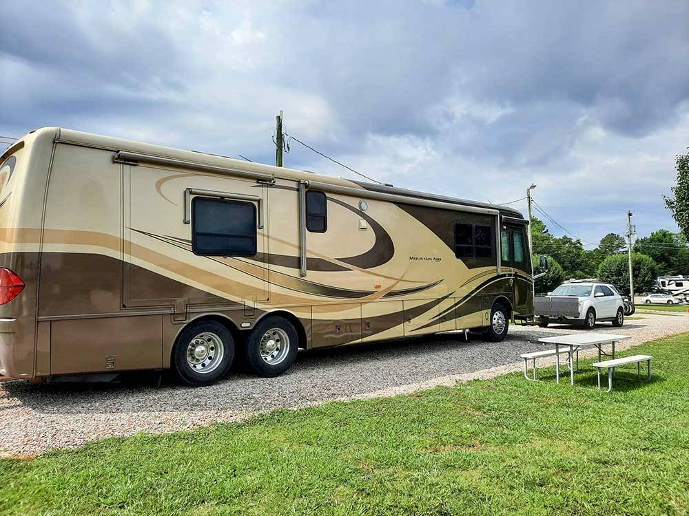 A large motorhome in a gravel RV site at GREEN ACRES RV PARK