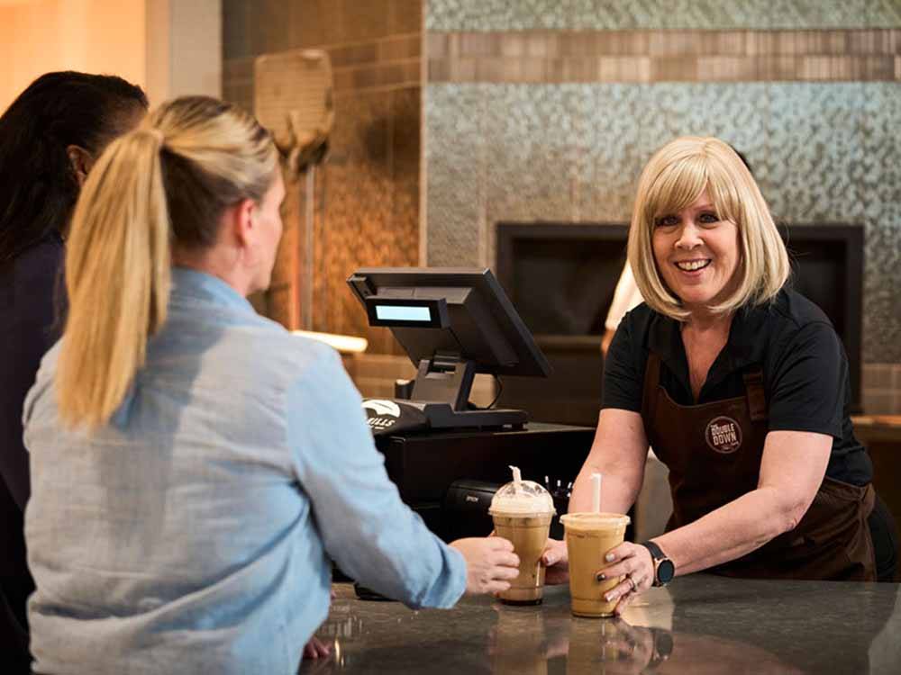A woman handing another woman a couple of coffees at THE RV PARK AT ROLLING HILLS CASINO AND RESORT