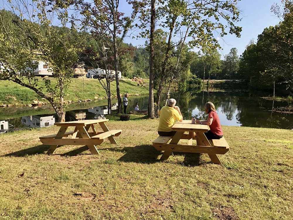 A couple sitting on a picnic bench overlooking the water at VALLEY RIVER RV RESORT