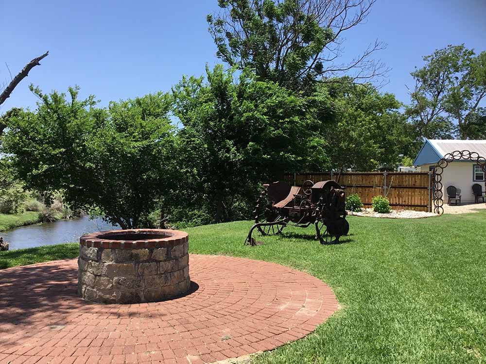 A stone fire pit in a grassy area at FLAT CREEK FARMS RV RESORT