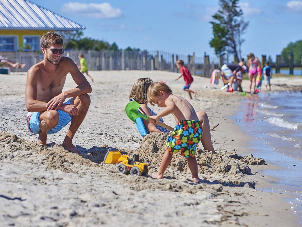 A dad watching his son playing in the sand at SUN OUTDOORS REHOBOTH BAY