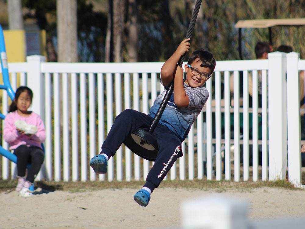 A boy having fun on a swing at SUN OUTDOORS REHOBOTH BAY