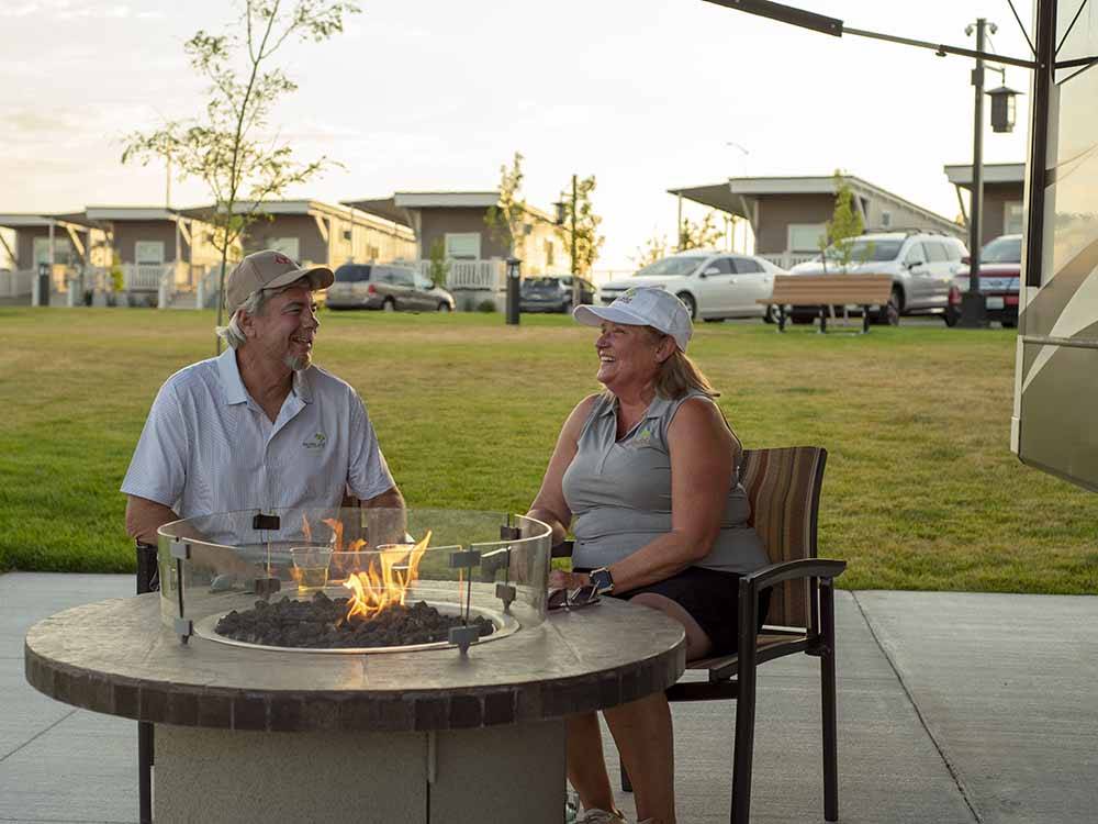 A couple sitting around a gas fire pit at NORTHERN QUEST RV RESORT