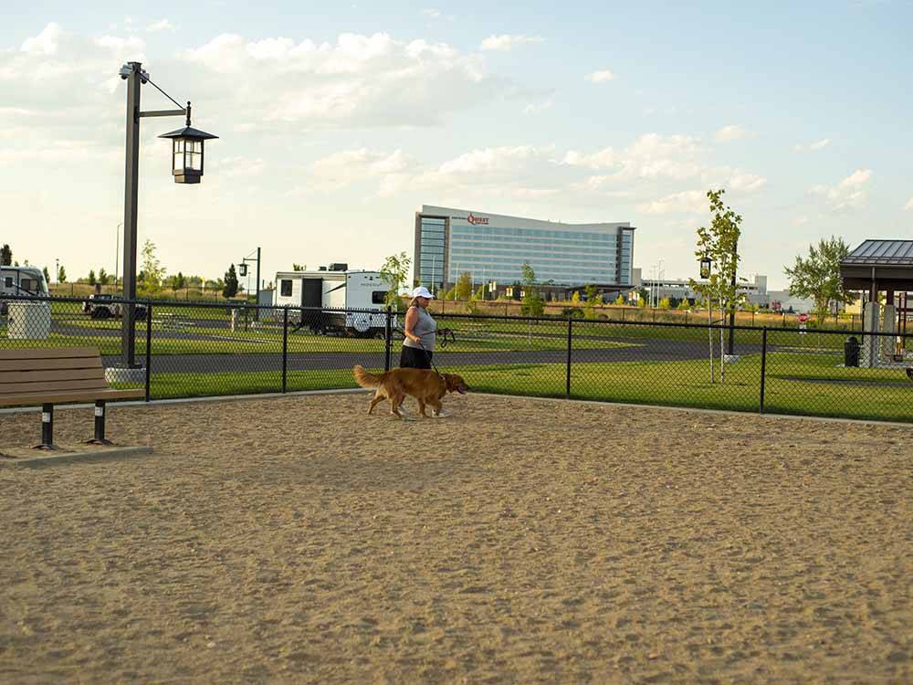 A woman walking her dog in the pet area at NORTHERN QUEST RV RESORT
