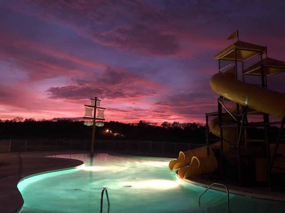 The outdoor pool lit up at night at AHOY RV RESORT