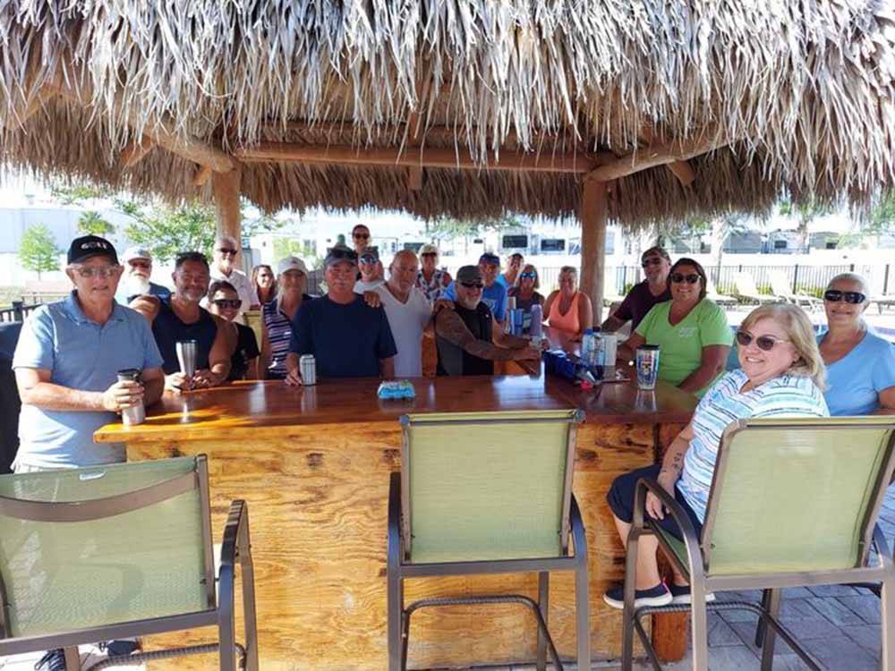 A group of people standing around the outdoor bar at SUNKISSED VILLAGE RV RESORT