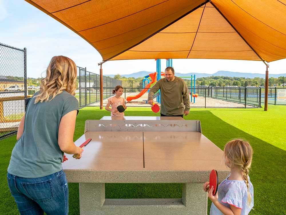A family playing ping pong outdoors at LURAY RV RESORT & CAMPGROUND ON SHENANDOAH RIVER
