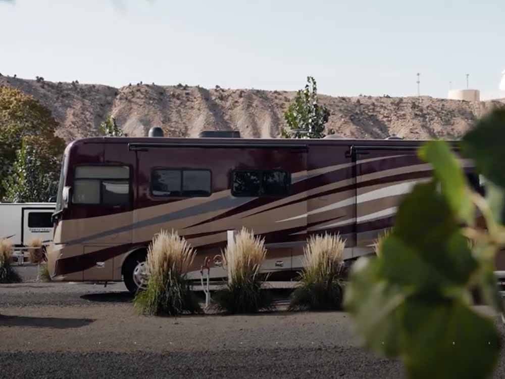 A dark and light brown motorhome in a gravel site at CASTLE GATE RV PARK & CAMPGROUND