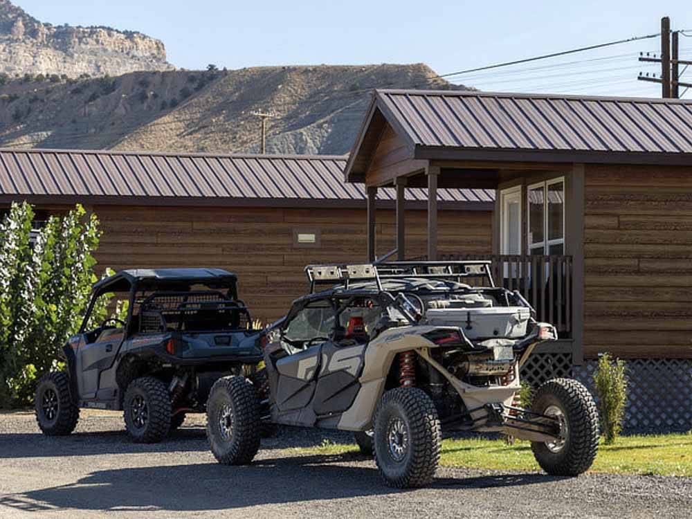 Two ATVs parked in front of a cabin at CASTLE GATE RV PARK & CAMPGROUND
