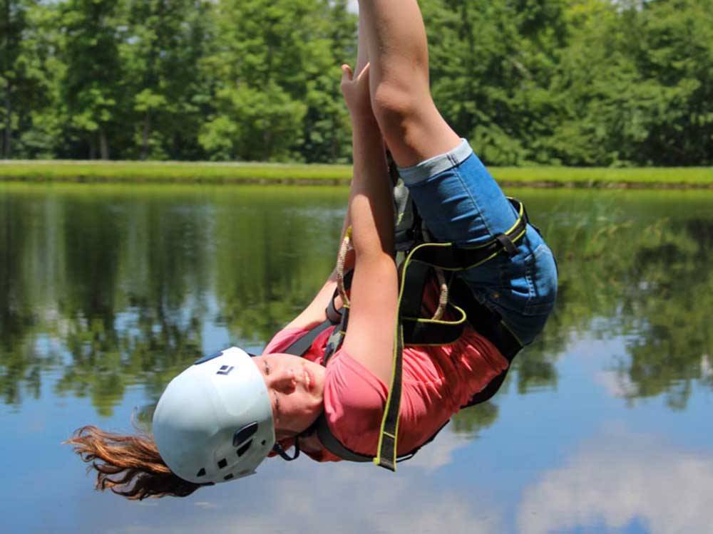 A young child ziplining over the pond at BIGFOOT ADVENTURE RV PARK & CAMPGROUND