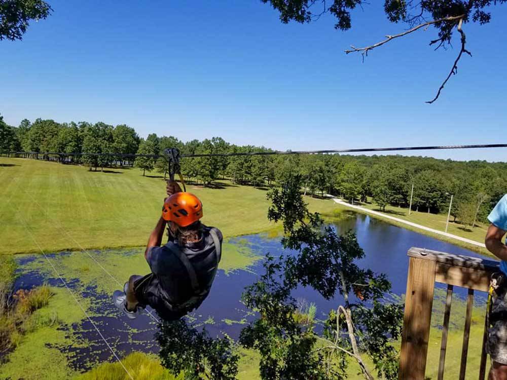A man zip lining over the pond at BIGFOOT ADVENTURE RV PARK & CAMPGROUND