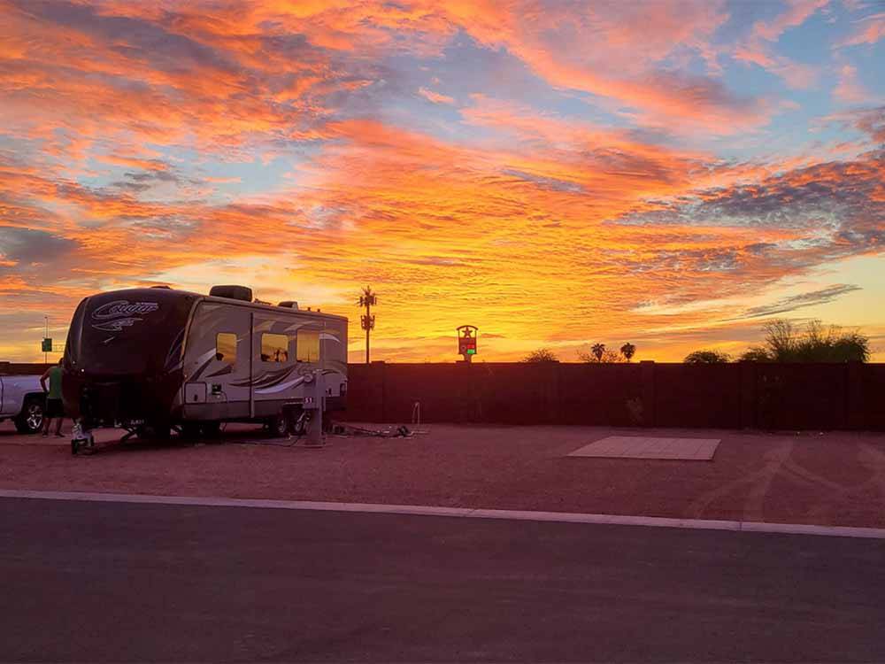 A travel trailer parked under the sunset skies at CAMPGROUND USA RV RESORT