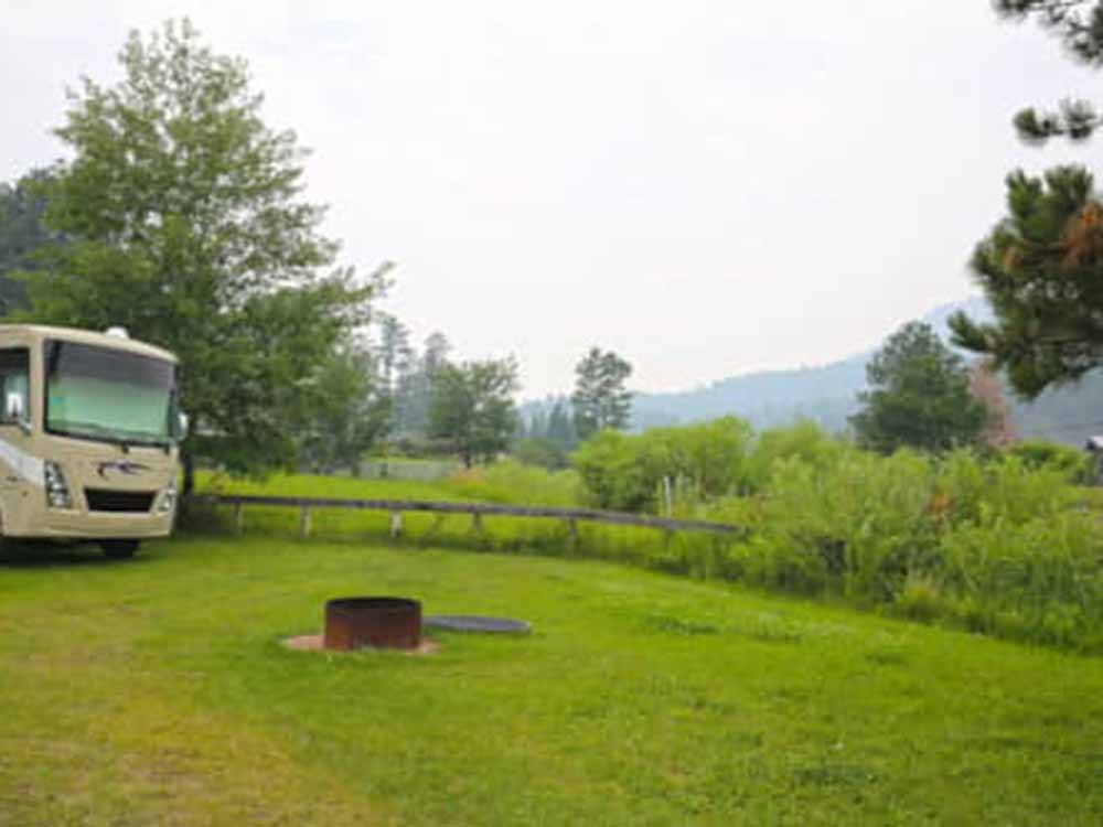 Motorhome parked on the grass near a fire pit at FIREHOUSE CAMPGROUND